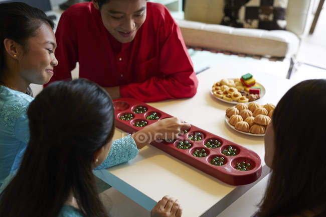 Familia asiática joven celebrando Hari Raya en Singapur y jugando juego tradicional - foto de stock