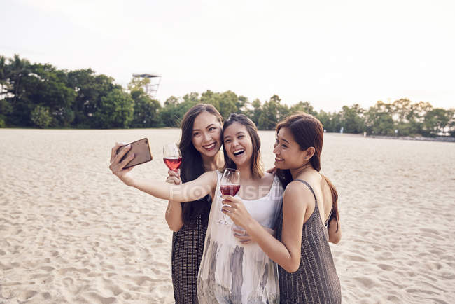 Attractive young asian friends having drink and taking selfie — Stock Photo