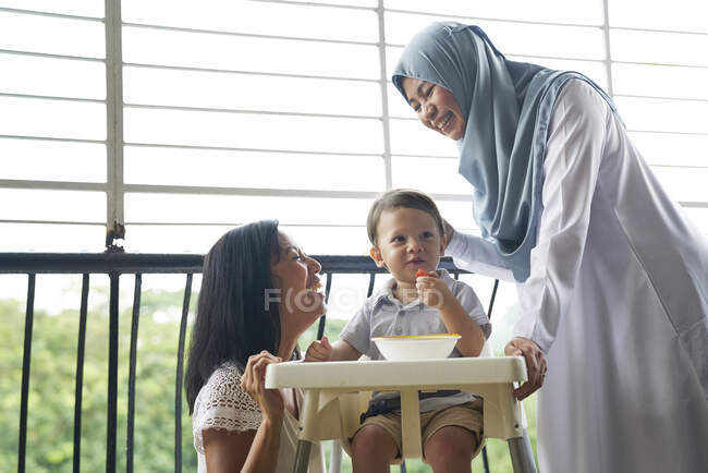Бабуся і мати зв'язуються з дитиною на балконі — стокове фото