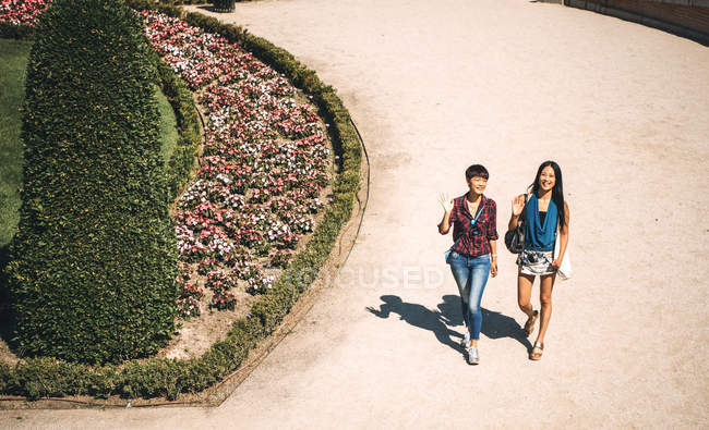 Niñas turísticas chinas y japonesas dando un paseo por el parque del Retiro, Madrid, España en un día soleado . - foto de stock