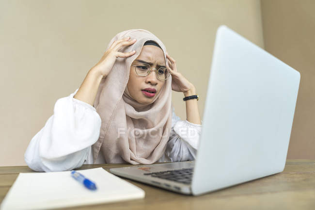 Young asian muslim woman using laptop indoors — Stock Photo