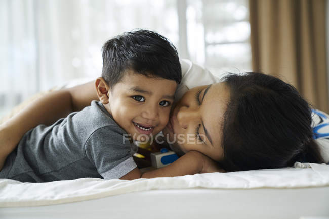 Азиатская мать связывается со своим сыном на кровати — стоковое фото