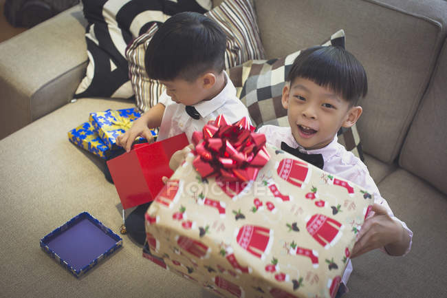 Boys happily celebrating Christmas in Singapore and opening their gifts. — Stock Photo