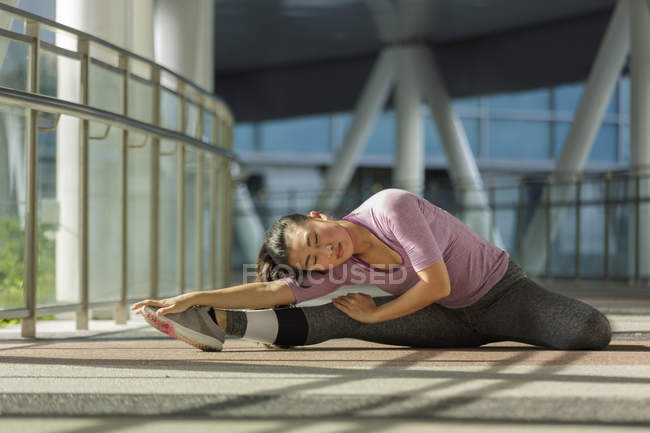 Eine junge asiatische Frau dehnt sich vor ihrem täglichen Lauftraining in Singapore — Stockfoto