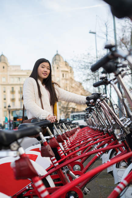 Jovem chinesa alugando uma bicicleta em Barcelona — Fotografia de Stock