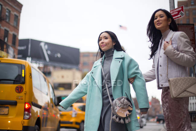 Duas belas mulheres asiáticas pegando táxi juntos em Nova York, EUA — Fotografia de Stock