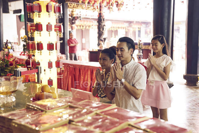 Feliz asiático familia orando juntos en tradicional singapurense santuario - foto de stock