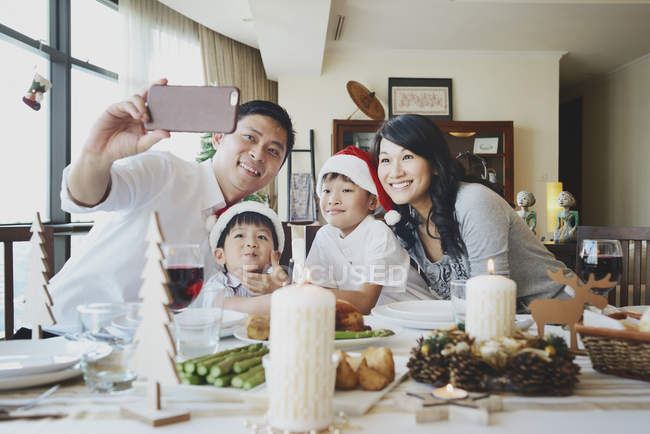 Felice famiglia asiatica che celebra il Natale insieme a casa e scattare selfie — Foto stock