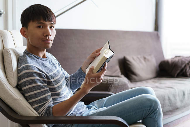 Дорослий азіатських юнак читання книги в домашніх умовах — стокове фото