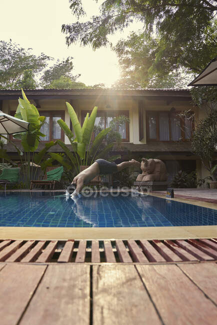 Молодий чоловік занурюється в басейн, вид збоку — стокове фото
