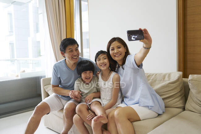 RILASCIO Felice giovane famiglia asiatica insieme prendendo selfie a casa — Foto stock
