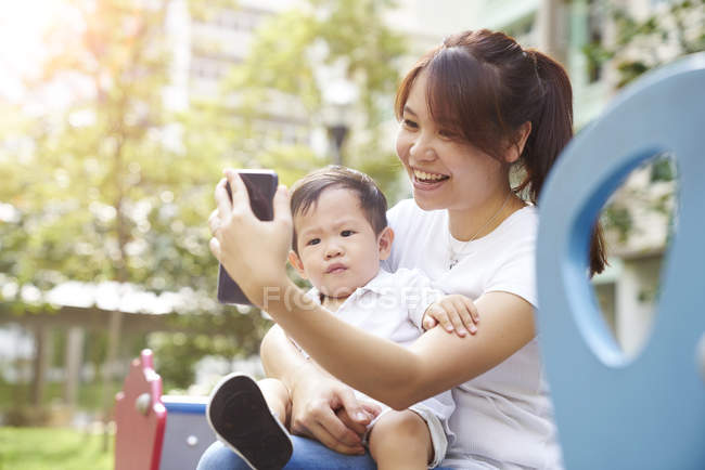 Молода мати бере селфі зі своєю дитиною в парку — стокове фото