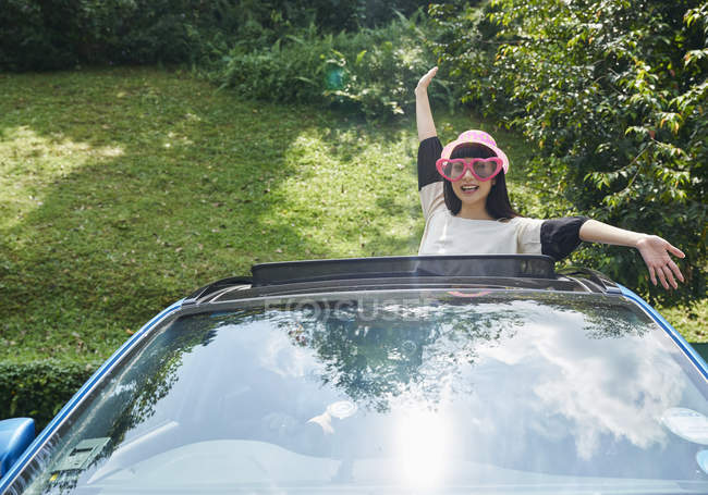 Woman standing outside the sun roof of a car — Stock Photo