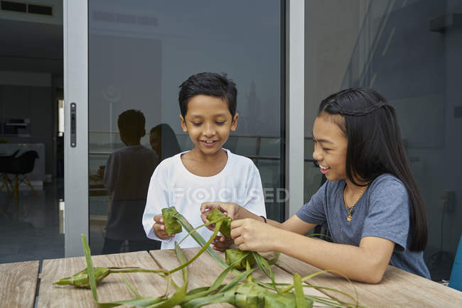 Молодые азиатские братья и сестры празднуют Хари Райя вместе дома и делают украшения — стоковое фото