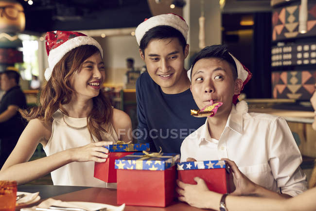 Feliz joven asiático amigos celebrando la Navidad juntos en la cafetería y compartir regalos - foto de stock