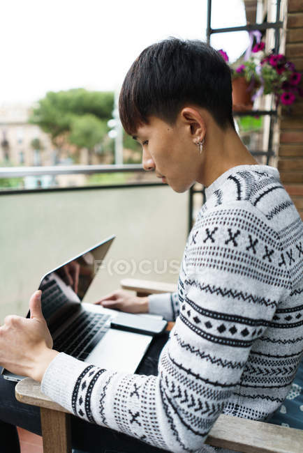 Young adult asian man using laptop at home — Stock Photo