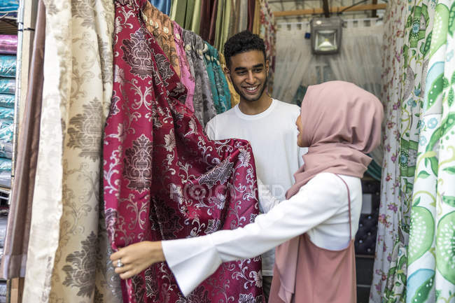 Joven pareja musulmana de compras para cortinas - foto de stock