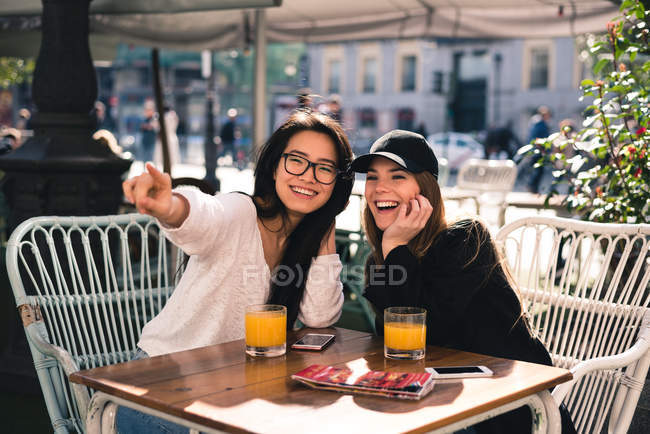 Dos hermosas amigas en la cafetería señalando algo - foto de stock