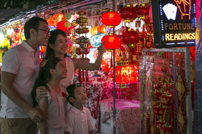 Счастливая семья, прогуливаясь по городу, глядя на красивые китайские новогодние украшения — стоковое фото