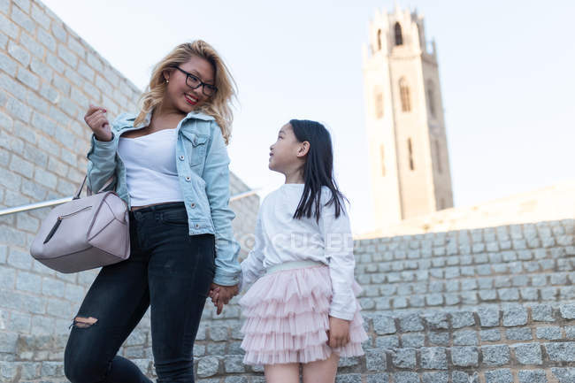 Счастливая молодая мать с дочерью спускается по лестнице — стоковое фото