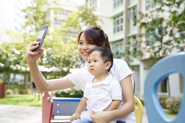 Jovem mãe tirando uma selfie com seu bebê no parque — Fotografia de Stock