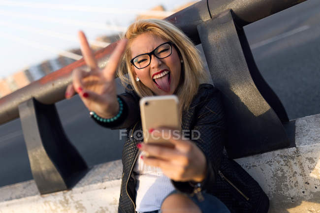 Retrato de una hermosa joven usando su teléfono móvil en la calle. - foto de stock