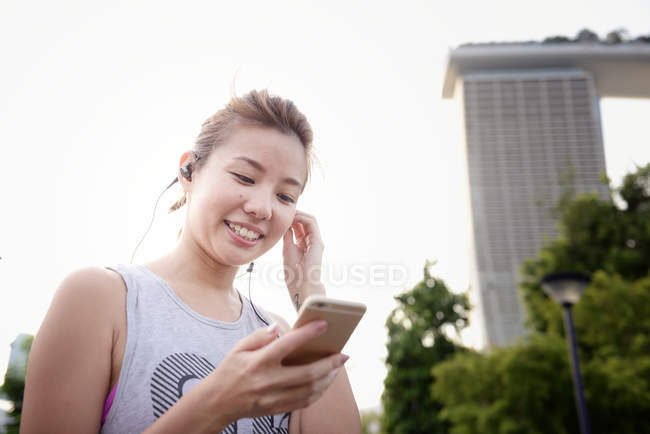 Jeune femme asiatique écoute de la musique dans les écouteurs — Photo de stock