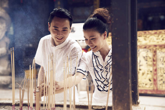 Jeune asiatique homme et femme prier dans temple avec joss bâtons — Photo de stock