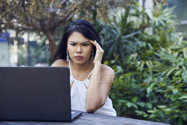 Joven mujer malaya frustrado mientras trabajaba en su computadora portátil - foto de stock