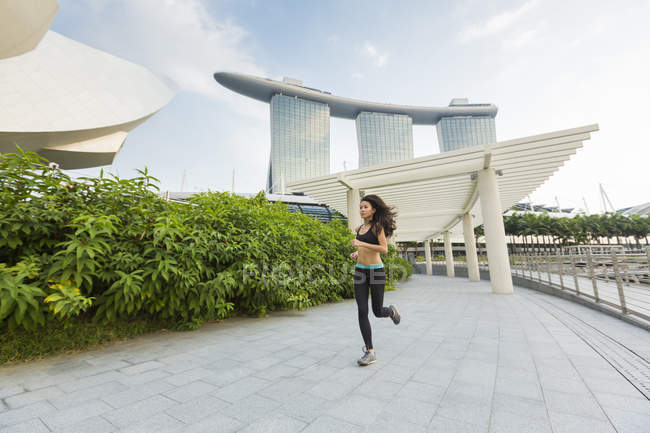 Una joven asiática está trotando en la bahía marina de Singapur . - foto de stock