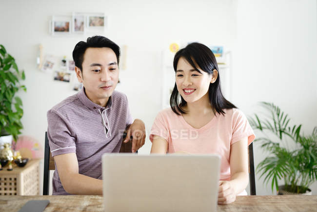 Adult asian couple together using laptop at home — Stock Photo