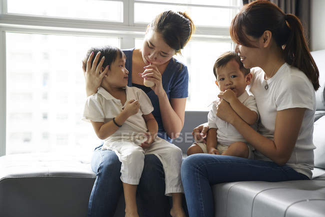 LIBERTAS Madres jóvenes que se unen a sus hijos en la sala de estar - foto de stock