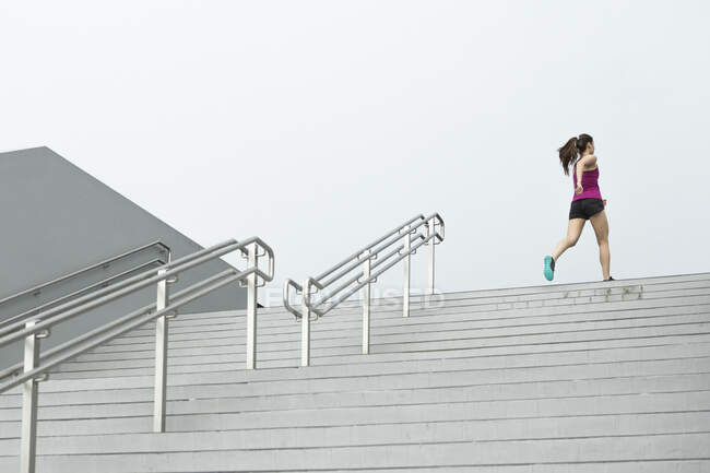 Un giovane asiatico, corridore femminile sta correndo su per una scala a Singapore . — Foto stock