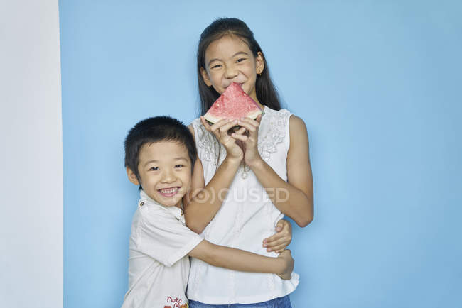 Happy young asian siblings eating watermelon — Stock Photo