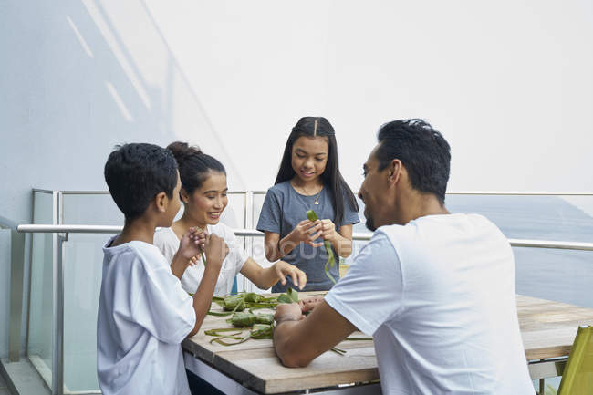 Молодая азиатская семья празднует Хари Райя вместе дома и делает украшения — стоковое фото