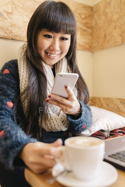 Молодий привабливою азіатські жінки за допомогою смартфона в кафе — стокове фото