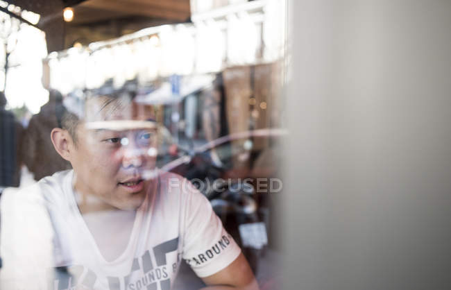 Portrait of ypung asian man behind window — Stock Photo