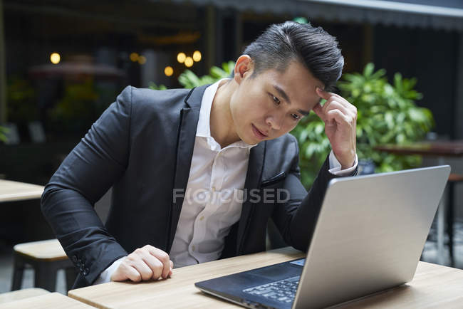 Молодой азиатский успешный бизнесмен с помощью ноутбука — стоковое фото