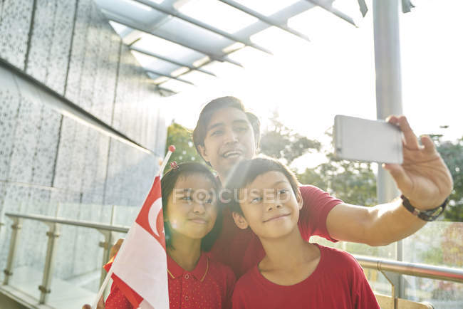 Famiglia felice che festeggia singapores la giornata nazionale — Foto stock