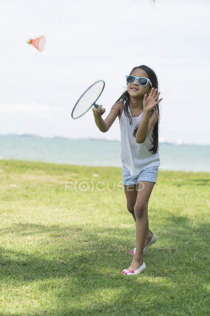 Молодая маленькая милая азиатская девочка с бадминтонной ракетой в парке — стоковое фото