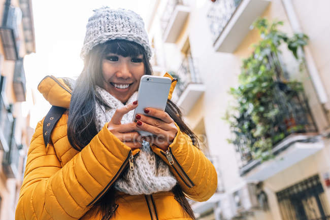 Молодая привлекательная азиатка, использующая смартфон на улице — стоковое фото