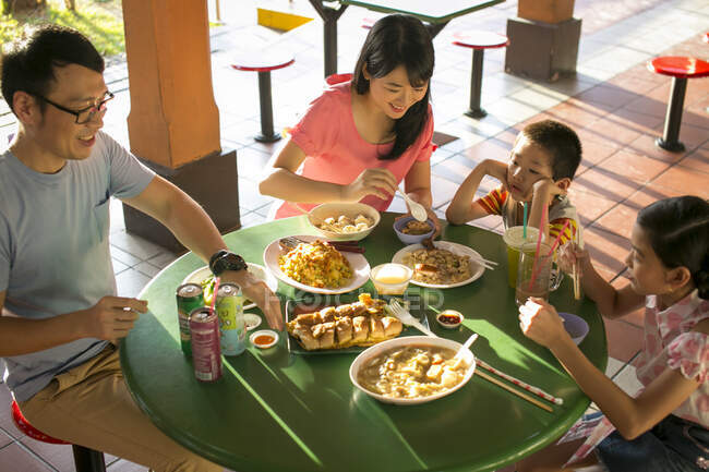 LIBERTAS Familia asiática feliz comiendo juntos en la cafetería - foto de stock