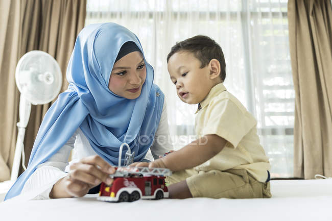 Young asian muslim mother and child having fun at home with toys — Stock Photo