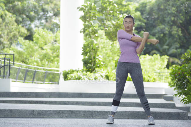 Une jeune femme asiatique s'étire avant son entraînement quotidien à Singapour — Photo de stock
