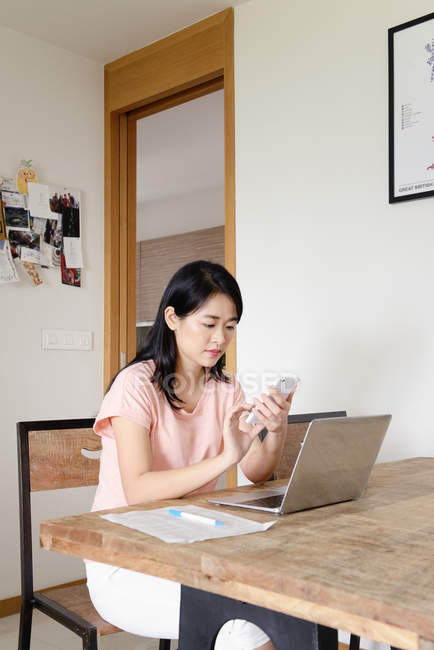 Jovem casual asiático mulher usando smartphone em casa — Fotografia de Stock