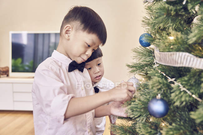 Щасливі азіатських родині святкування Різдва разом, хлопчики прикраси на ялинку — стокове фото