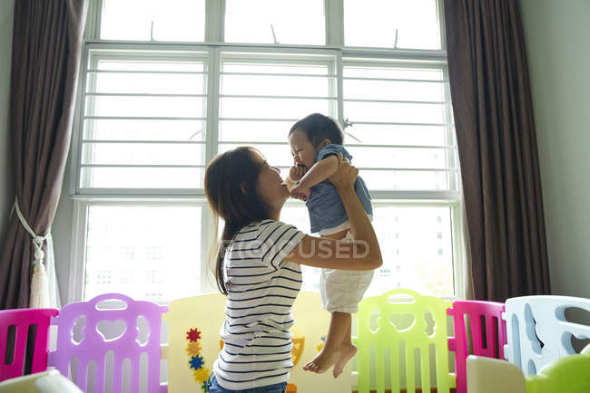 Asiatico madre portando il suo bambino in il gioco stanza — Foto stock