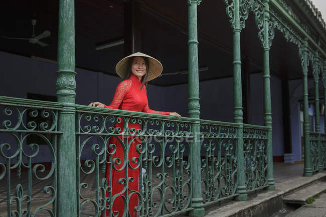 Mulher vietnamita usando chapéu cônico em pé em uma varanda em Hoi An em seu Ao Dai — Fotografia de Stock