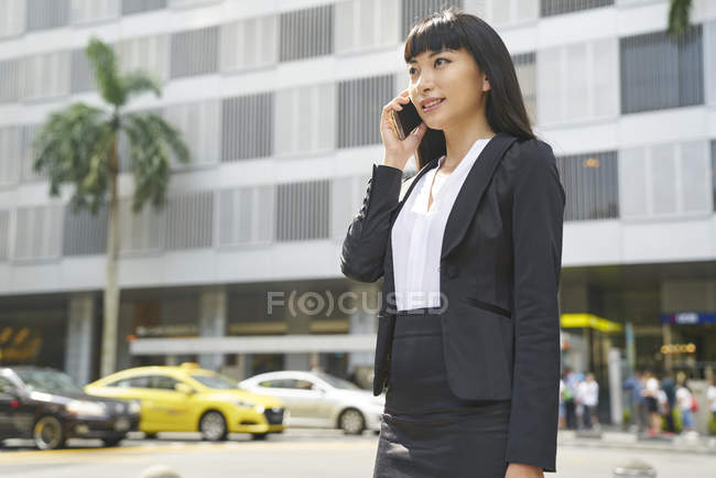 Jovem atraente asiático empresária usando smartphone na cidade — Fotografia de Stock