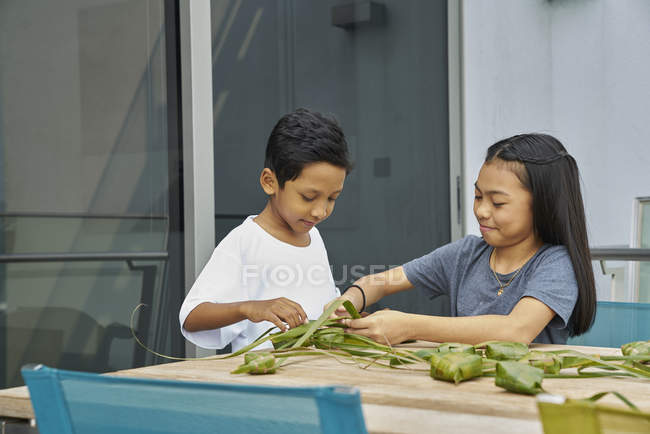 Jovem asiático irmãos celebrando hari raia juntos no casa e fazendo decorações — Fotografia de Stock